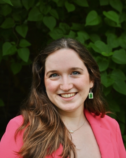 Photo of Kate Singer smiling and wearing a pink blazer